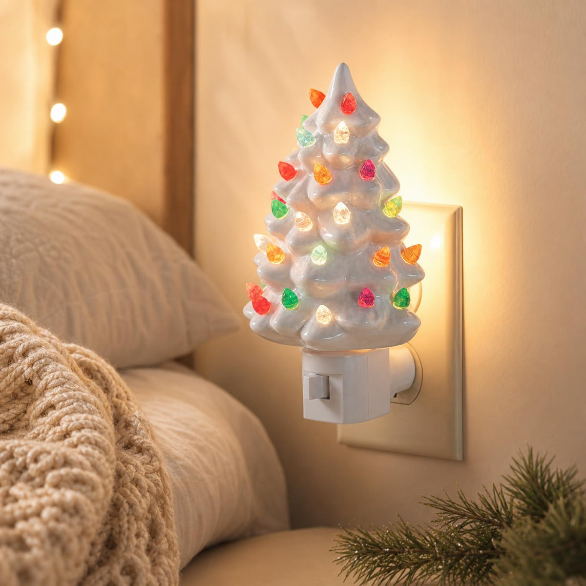 White Christmas tree night light next to a bed